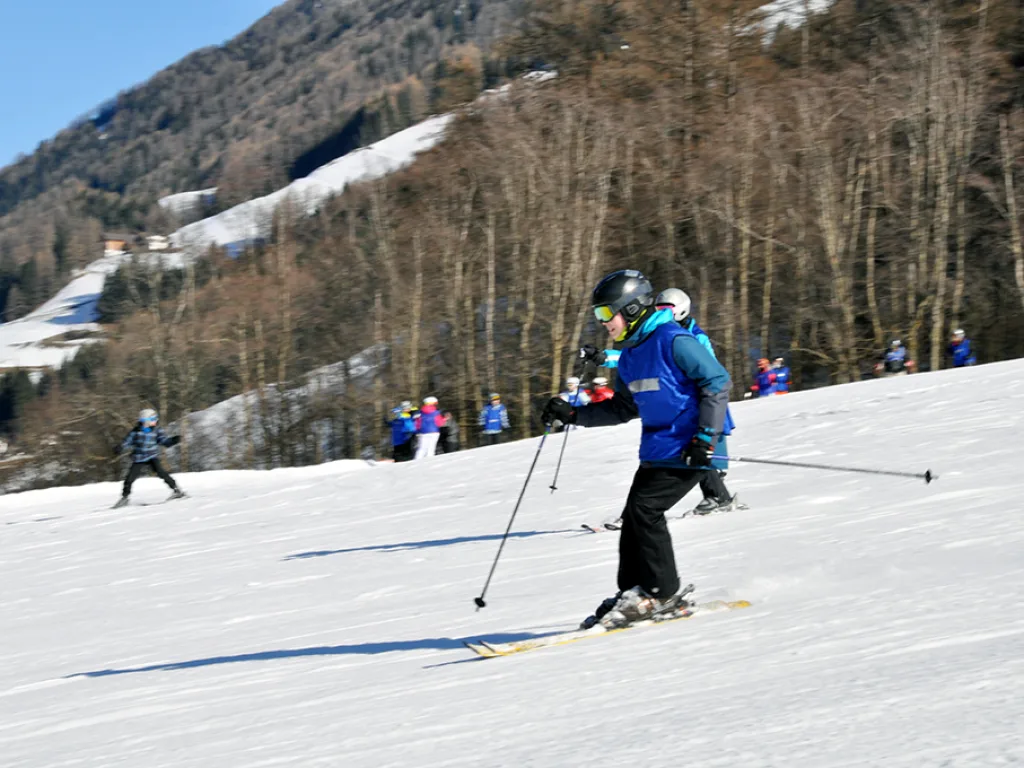 Skifahrer fährt an einem Hang vor einem Bauernhaus.